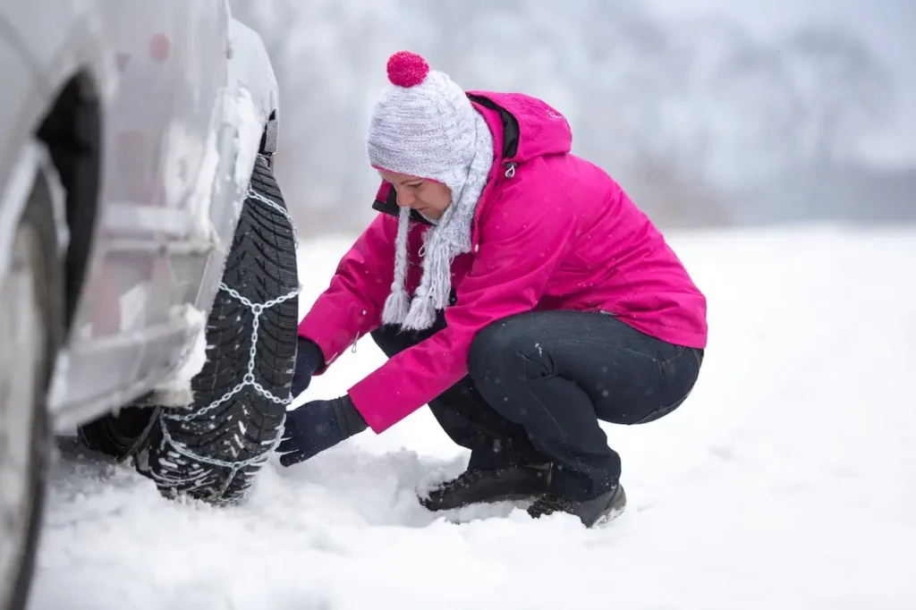 Mujer colocando cadenas para la nieve