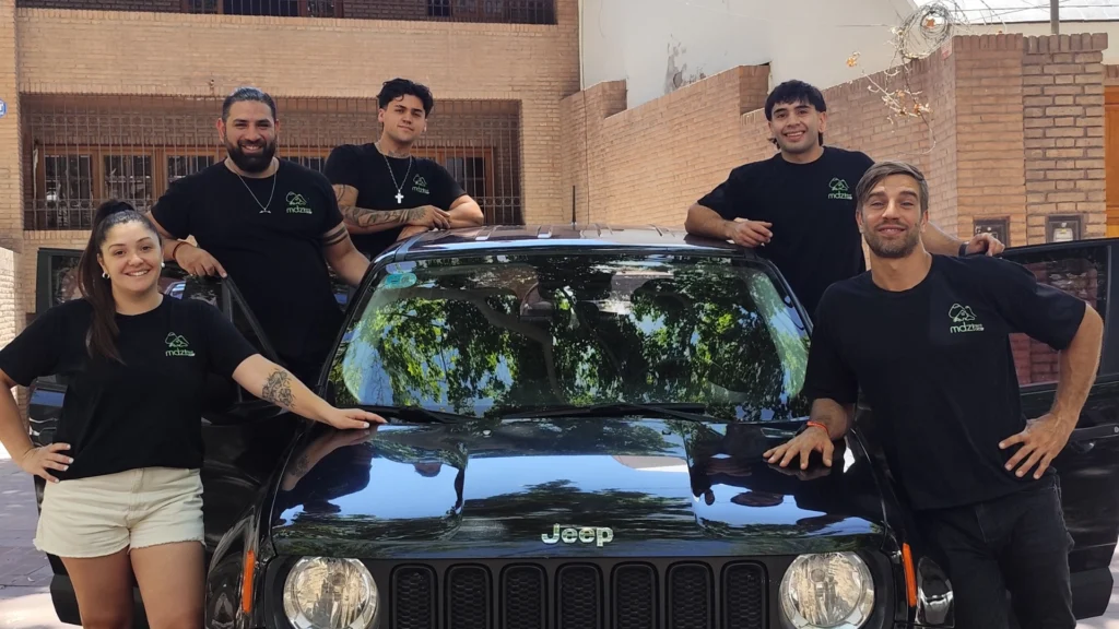 Equipe da MDZ Rent a Car ao lado de um veículo da frota