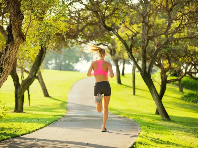 Mujer corriendo por un sendero arbolado del parque